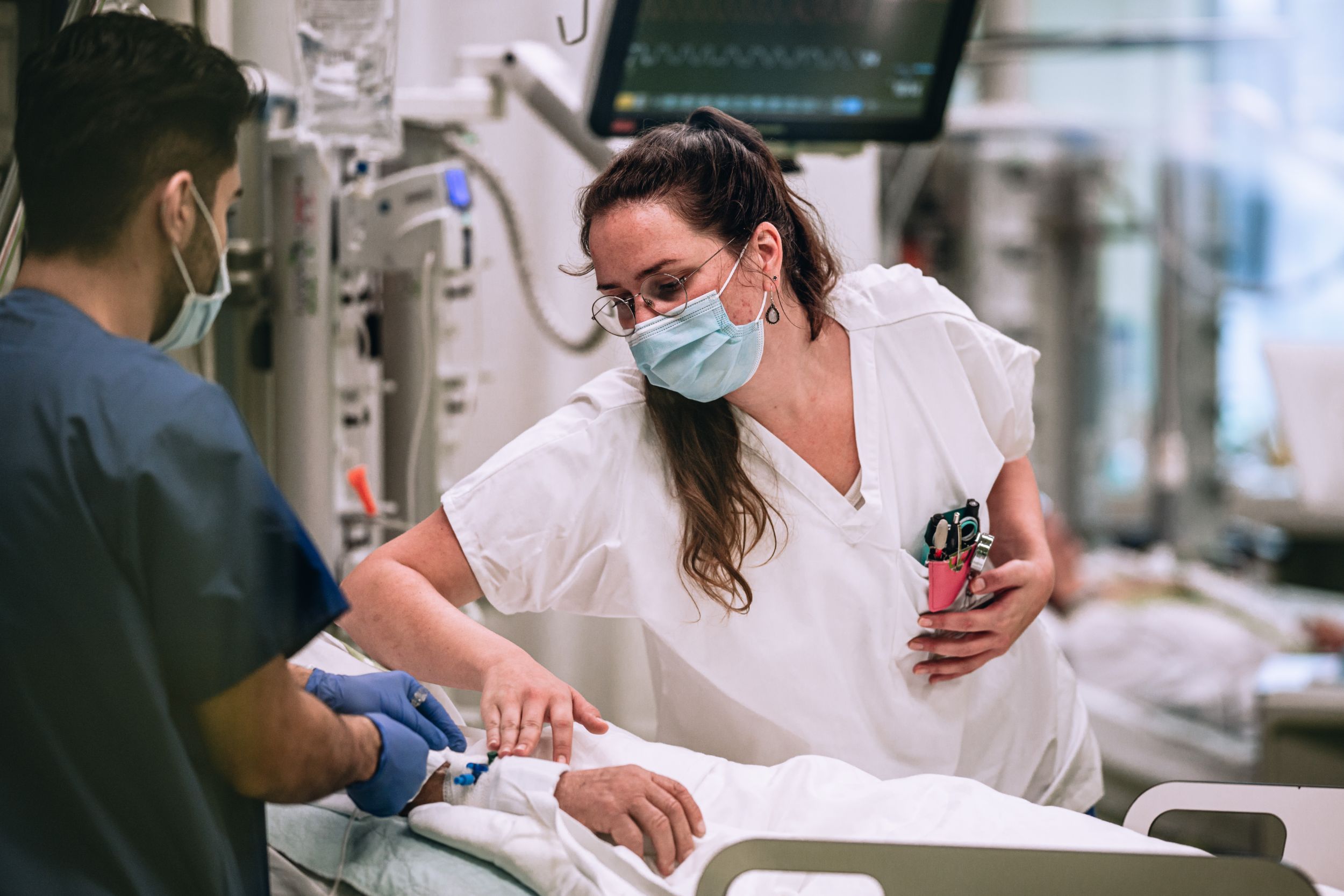 Zwei Pflegende behandeln eine Patientin oder einen Patienten auf der Intensivstation