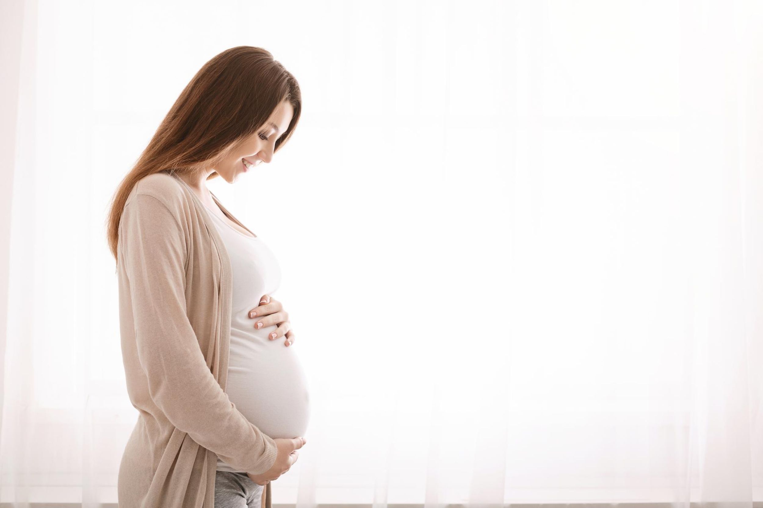 Eine schwangere Frau hält ihren Bauch.