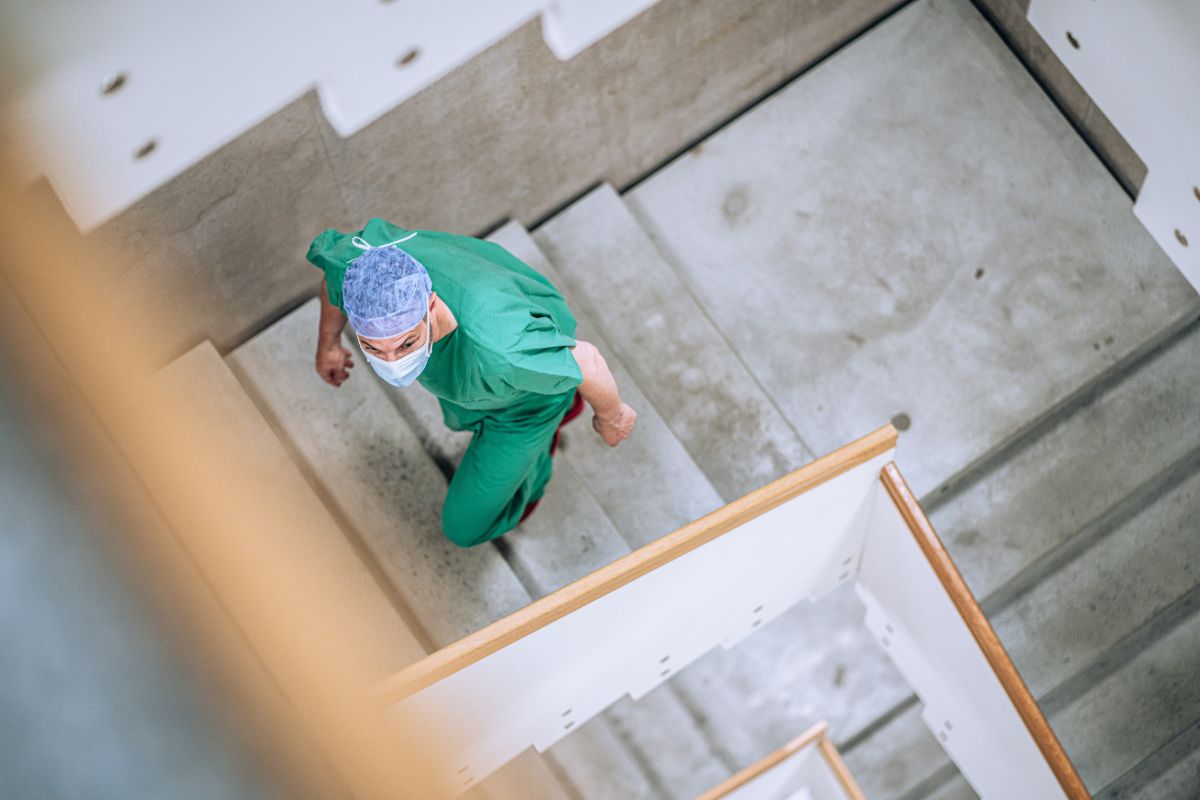 Arzt in OP Kleidung läuft die Treppe hoch