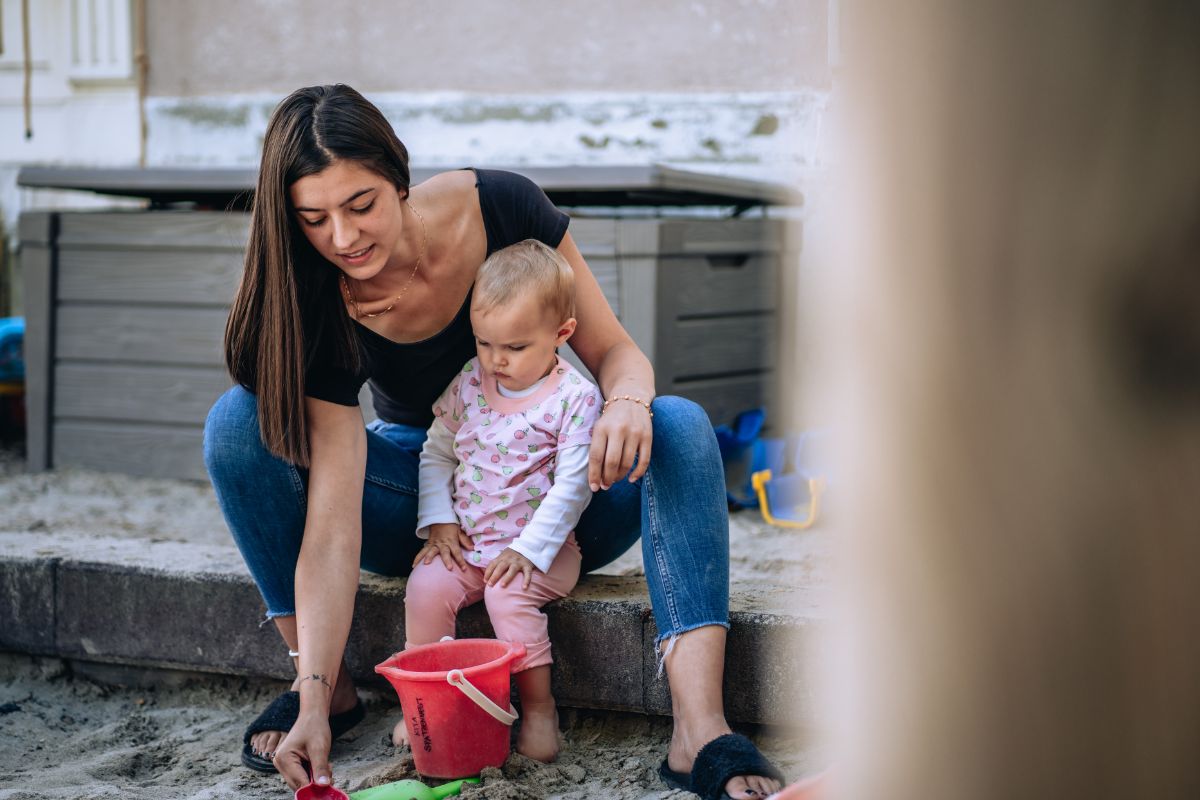 Fachfrau Betreuung spielt mit einem Kind auf dem Spielplatz