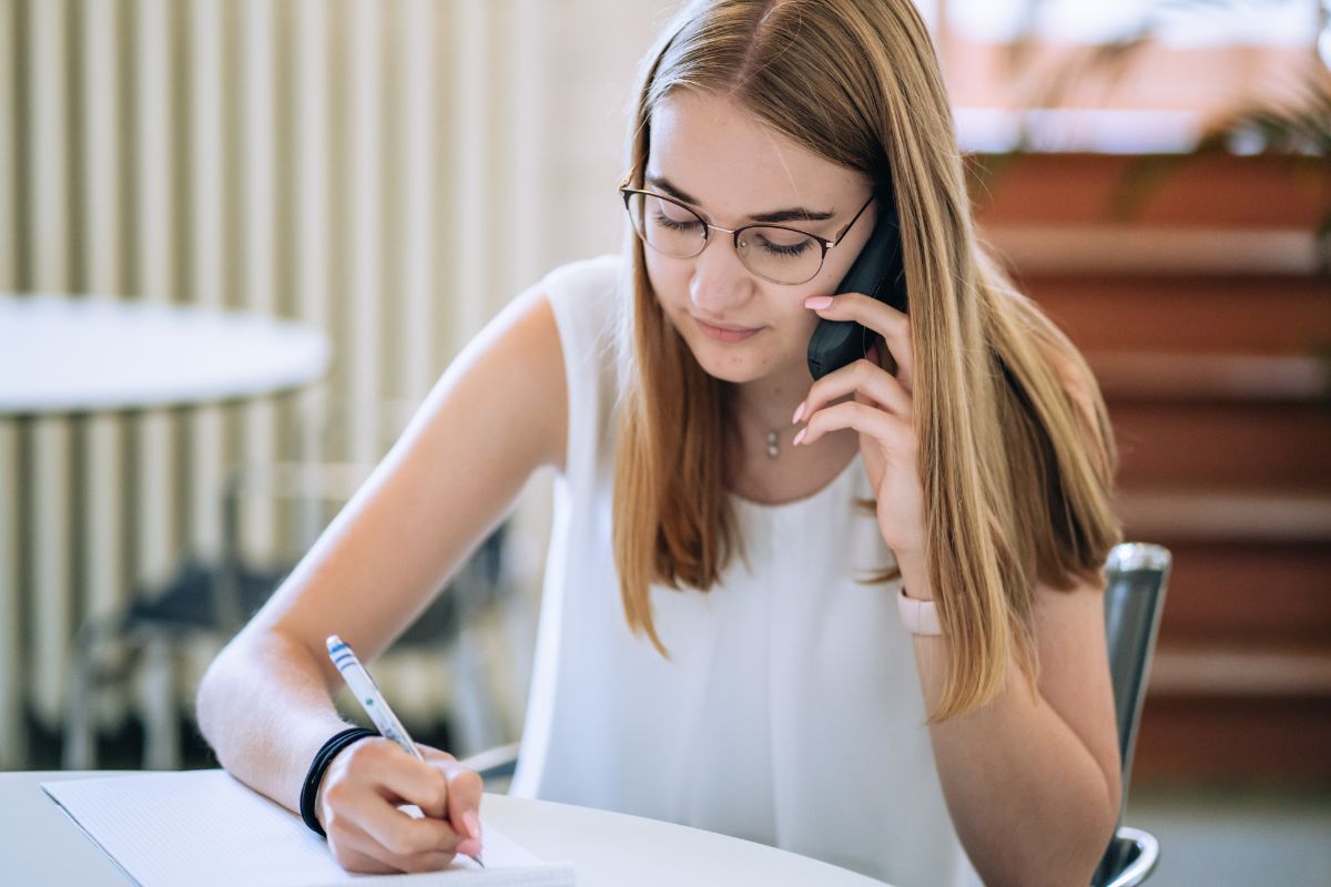 Büroassistentin telefoniert und macht sich Notizen