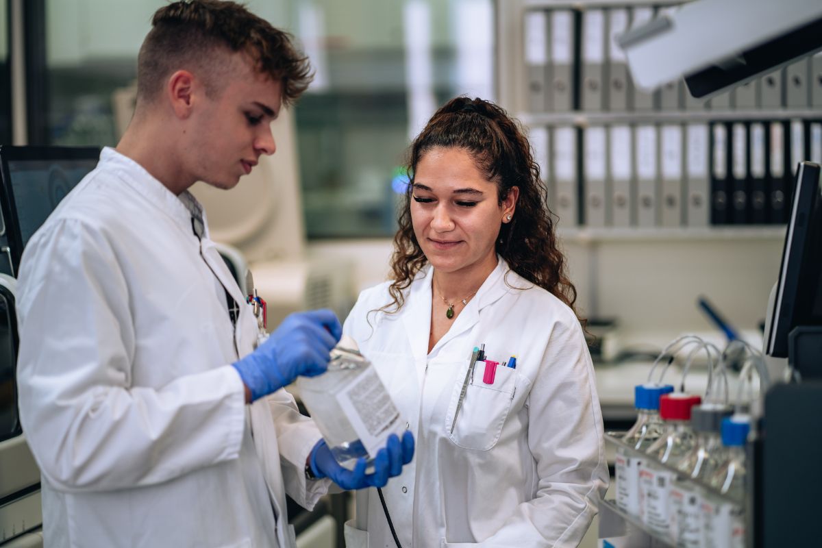 Eine Laborantin und ein Laborant in Ausbildung reden über ein medizinisches Equipment